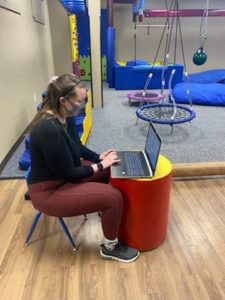 A therapist uses children's equipment to offer teletherapy services. 
